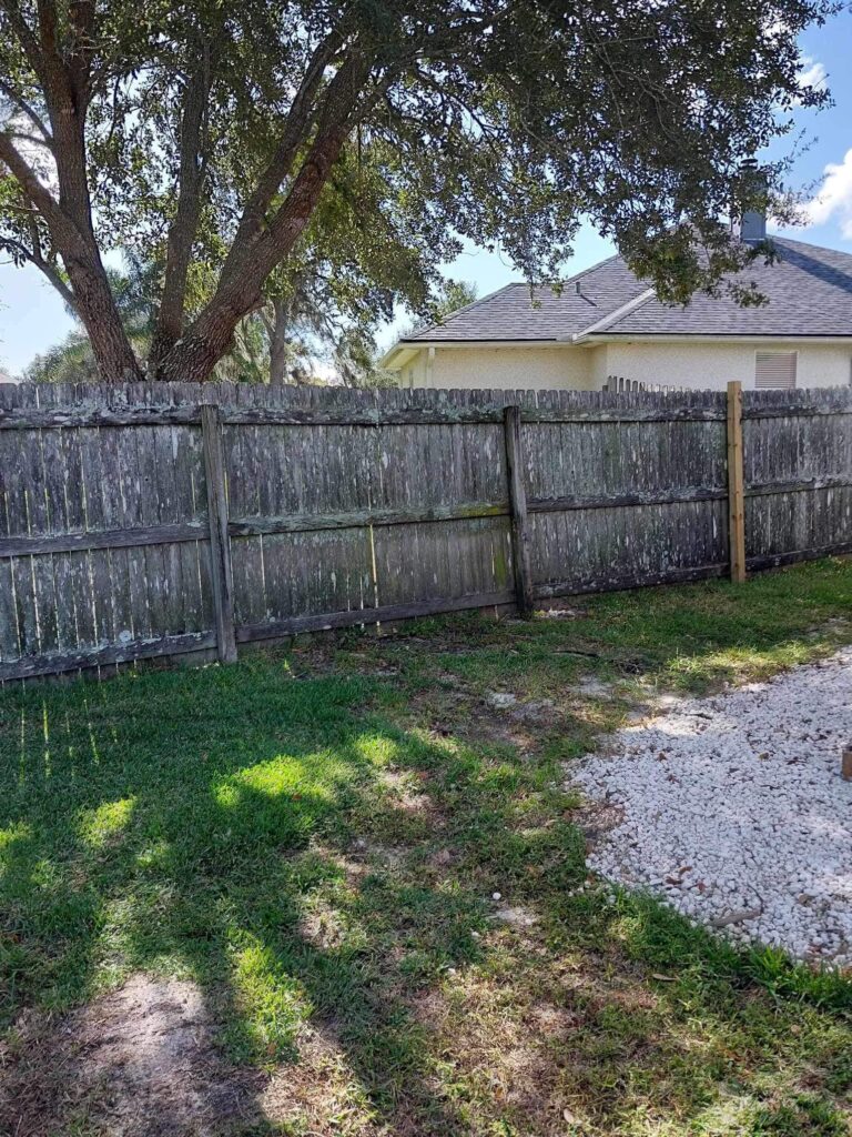 A weathered wood privacy fence on a Florida residential property, showing signs of age, moisture damage, and wear that may require inspection or repair.