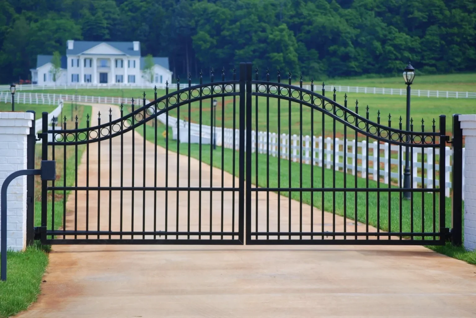 Decorative metal estate gate installed at a wide residential driveway entrance