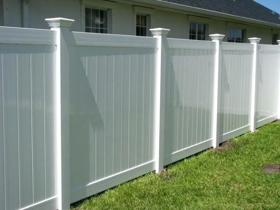 White vinyl privacy fence with decorative post caps installed at a residential property in Florida