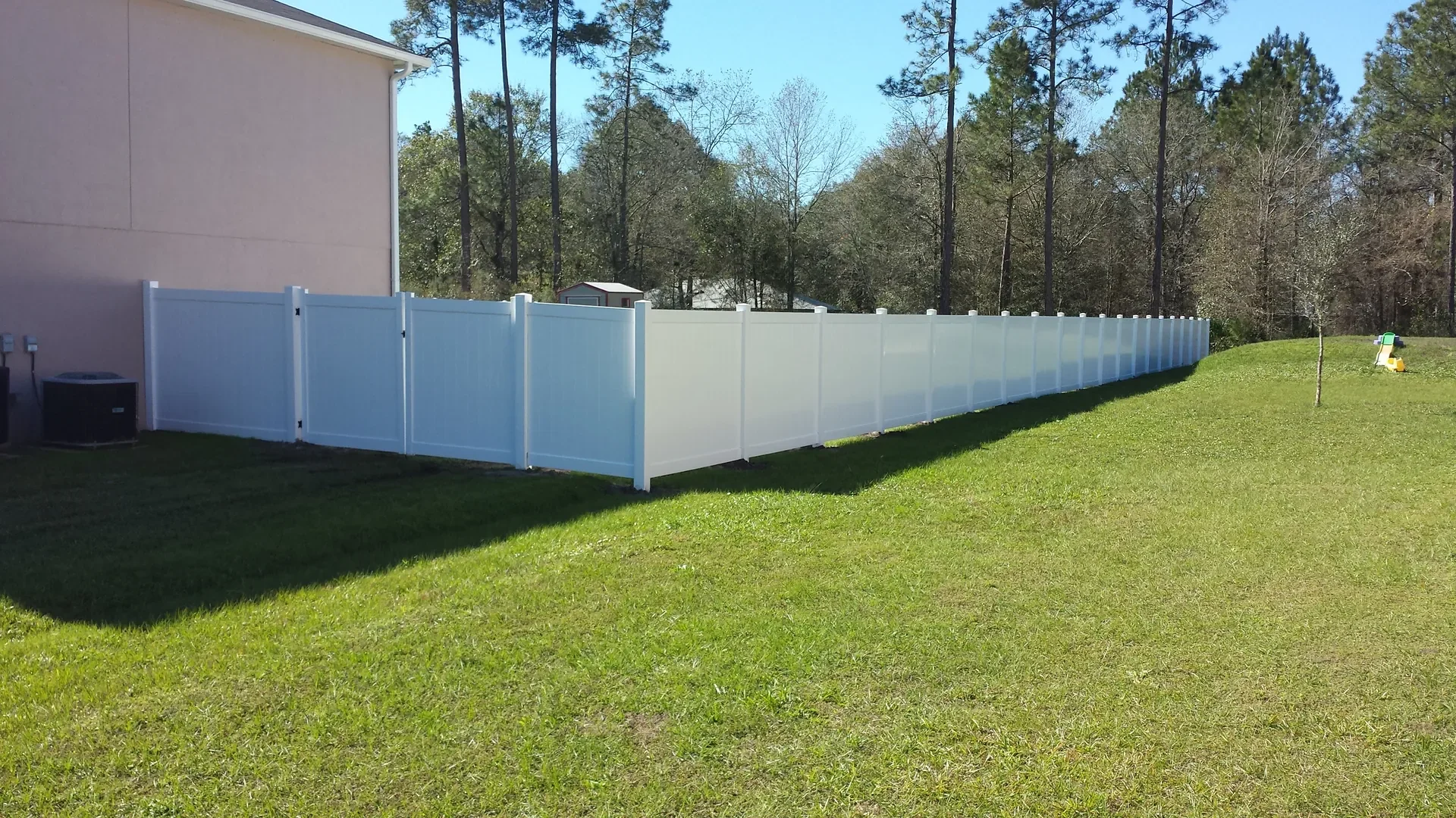 White vinyl privacy fence running along the side of a residential property with a green lawn in Florida