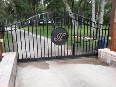 custom metal estate gate with decorative monogram at residential driveway entrance